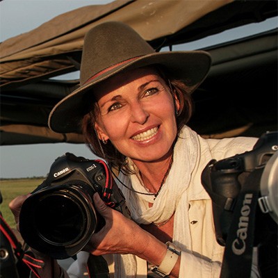 Photo of filmmaker Beverly Joubert wearing a hat and holding a camera