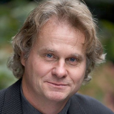 Photo of PhD Wade Davis with curly blond hair wearing a gray shirt
